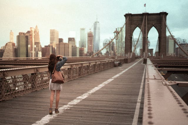 Junge Frau fotografiert auf der Brooklyn Bridge in New York